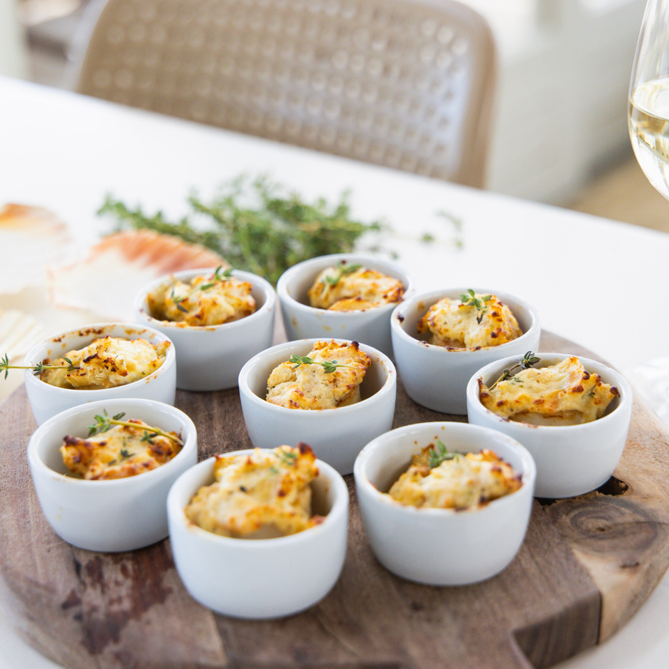 Gegratineerde coquilles in kleine ovenschaaltjes met een goudbruine crumble van crackers, oude kaas en verse kruiden