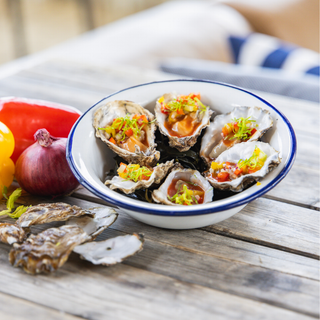 Verse Spéciale de Zélande oesters geserveerd met een pittige Bloody Mary cocktail dressing in een wit geëmailleerd bord